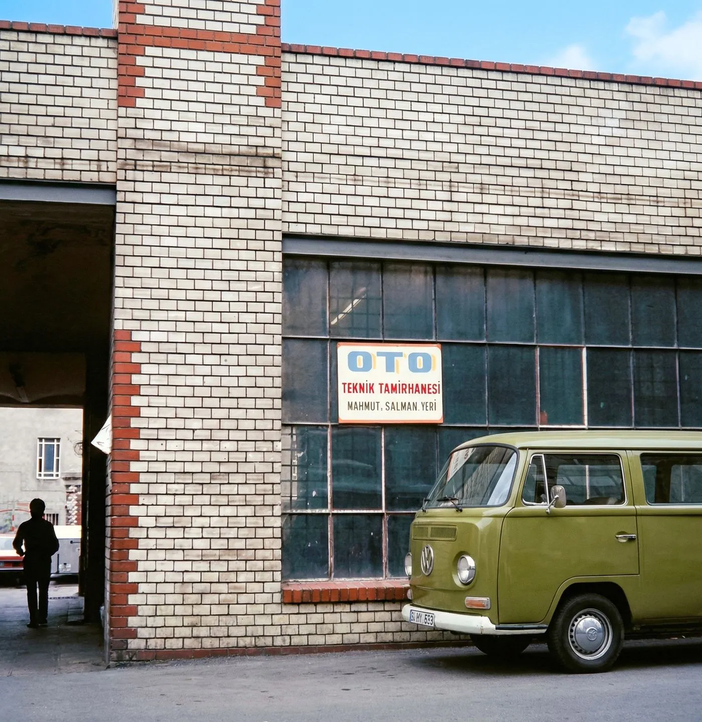 Fachada de oficina mecânica de bairro com uma kombi estacionada